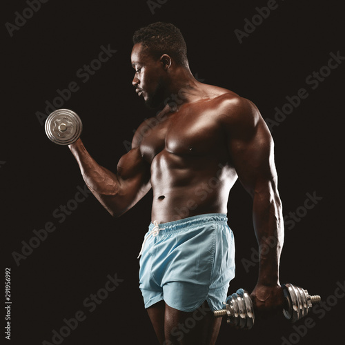 Portrait of black bodybuilder doing single arm dumbbell curl