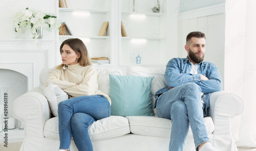 Young couple sitting on different sides of couch after quarrel Young couple sitting on different sides of couch after quarrel