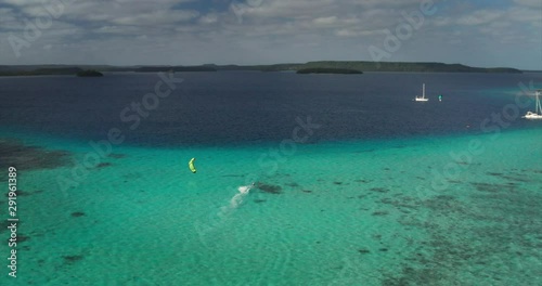 Aerial shot of kitesurfer in riding waves with water splash in a blue sea on a sunny day.