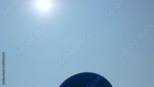 Planet earth representation balloon moving in the wind on a sunny day in Berlin, Germany with lens flare