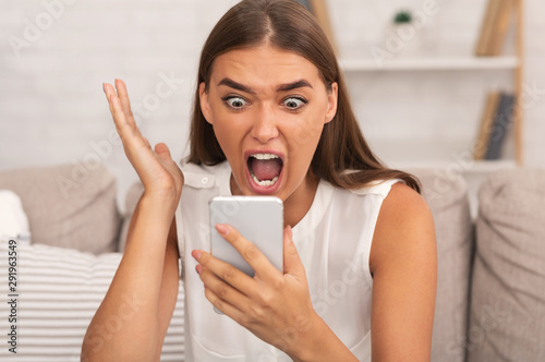 Furious Girl Screaming On Phone Sitting On Couch Indoor