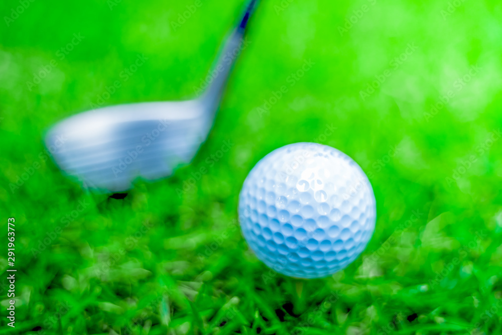 Naklejka premium golf ball close-up in soft focus at sunlight with Green grass. wide landscape as background ,Sport playground for golf club concept.shallow focus effect.