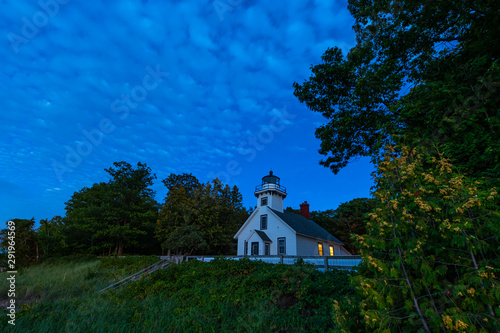 Old Mission Point Lighthouse at twilight showing lights in windows, at the 45th parallel on Old Mission Peninsula, Traverse City, Michigan.
