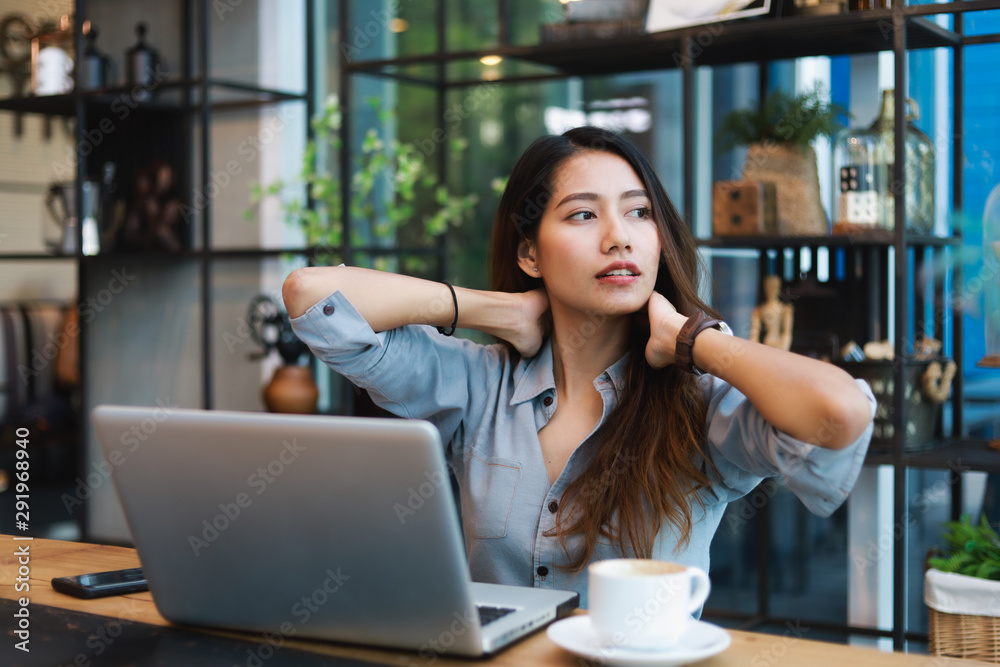 Asian woman in blue shirt working and drink coffee in coffee shop cafe vintage color tone Asian woman in blue shirt working and drink coffee in coffee shop cafe vintage color tone