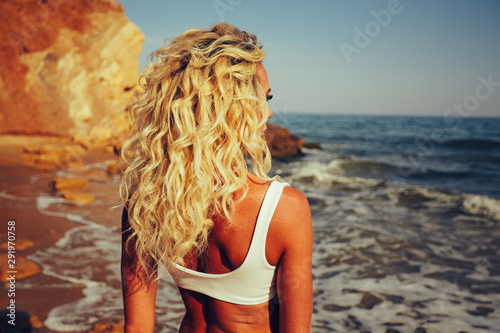 Blonde curly hair tan girl watching ocean