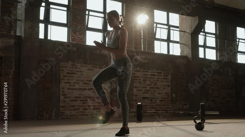 Workout. Woman doing high knees running in place exercise at gym