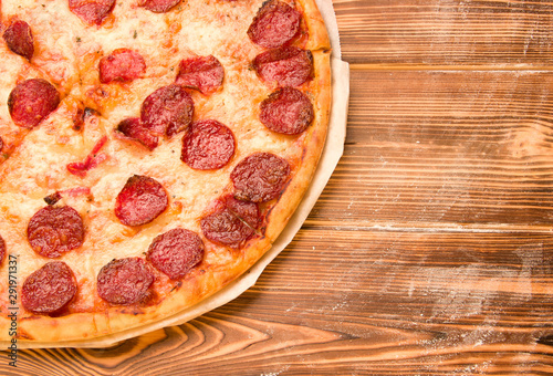 Pizza with salami on a wooden table. Dinner.