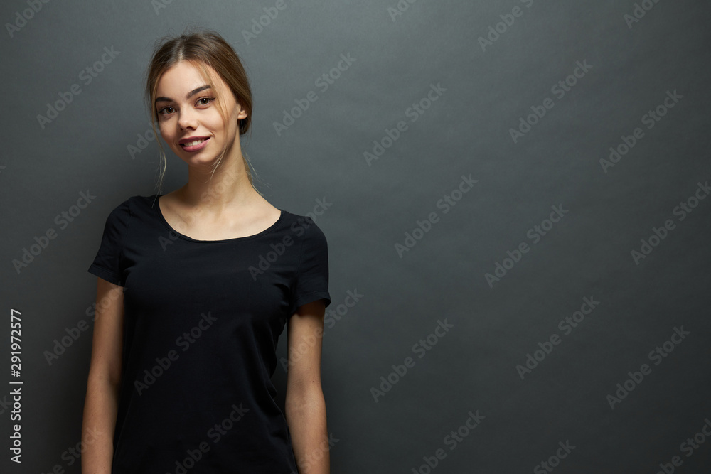 Sexy woman or girl wearing black blank t-shirt with space for your logo, mock up or design in casual urban style over gray background Sexy woman or girl wearing black blank t-shirt with space for your logo, mock up or design in casual urban style over gray background