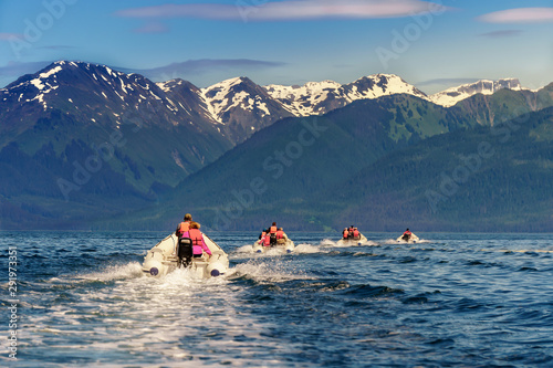 Coastal exploration by zodiac. Icy Strait Point, Alaska. Excursion by motor boat. Four boats with amazing view on snow mountains. Blue water and green hills.