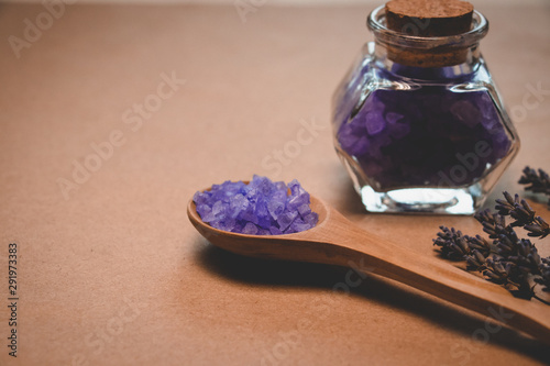 Lavender salt in wooden spoon, decorative bottle, lavender on a craft background.