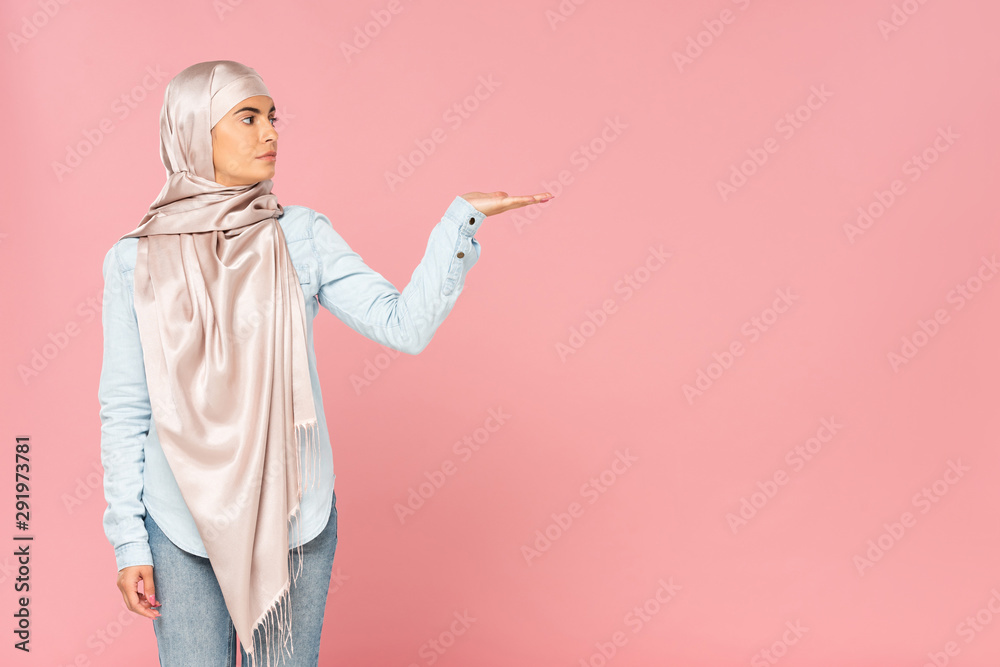 beautiful muslim woman in hijab showing something, isolated on pink beautiful muslim woman in hijab showing something, isolated on pink