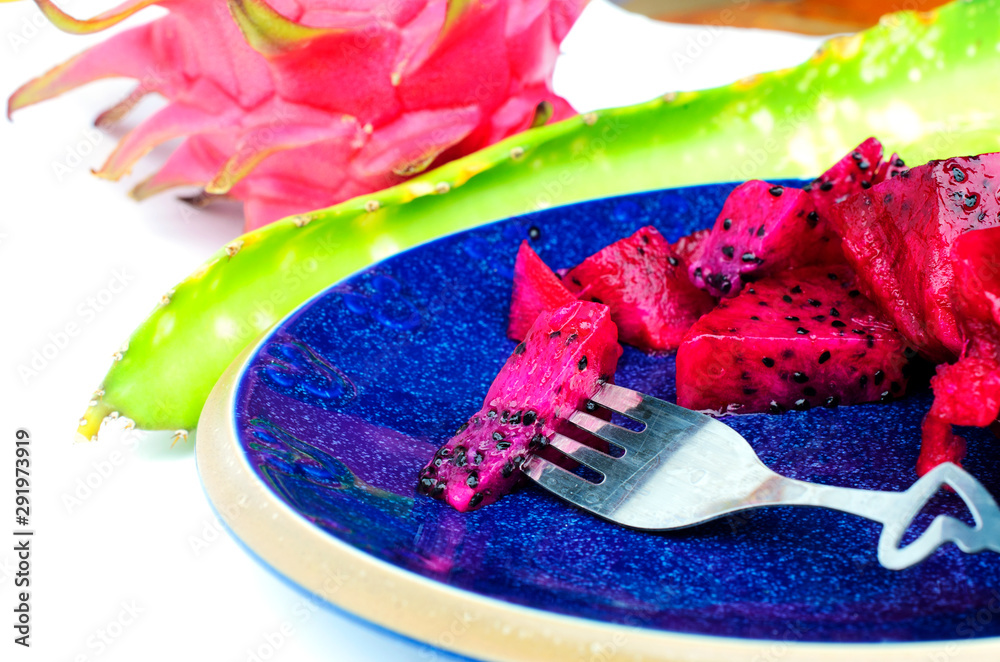 Close uo of a fork with sliced dragon fruits on blue dish for health food and weight loss backgrounds Close uo of a fork with sliced dragon fruits on blue dish for health food and weight loss backgrounds