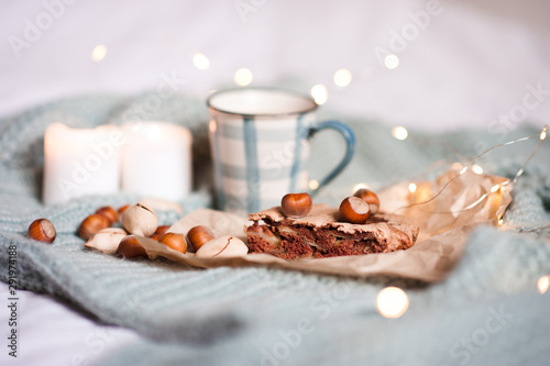 Sweet chocolate pie aith nuts and hot cup of tea over Christmas lights at background. Winter holiday season. Tasty breakfast. Good morning. photo