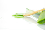 Aloe vera fresh leaves with slices and gel on wooden spoon on white background.