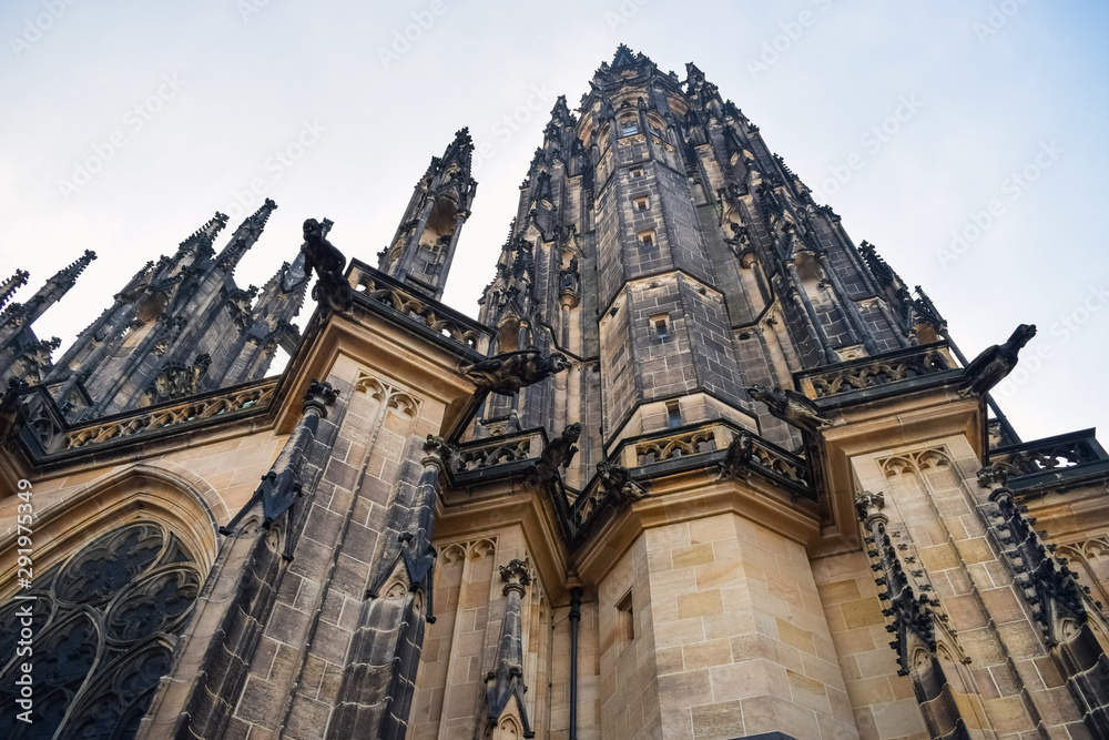 View from below on tall ancient the St. Vitus Cathedral with statues in Prague