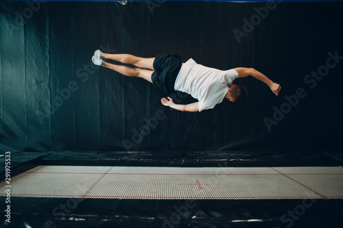 Quadro su tela Young male acrobat jumping on a trampoline