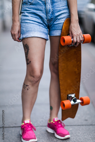 a tattooed girl holds a longboard in her hands