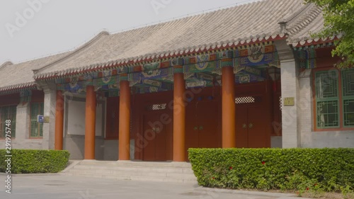 A daylight medium shot of the entrance to the Beijing Changpu River Park in China decorated with thick columns painted in orange and traditional clay tiles on the roof.. photo