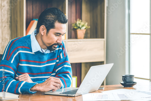 Arab businessman in casual clothes  working in the office with laptop, paper, note and a cup of coffee on working table.
