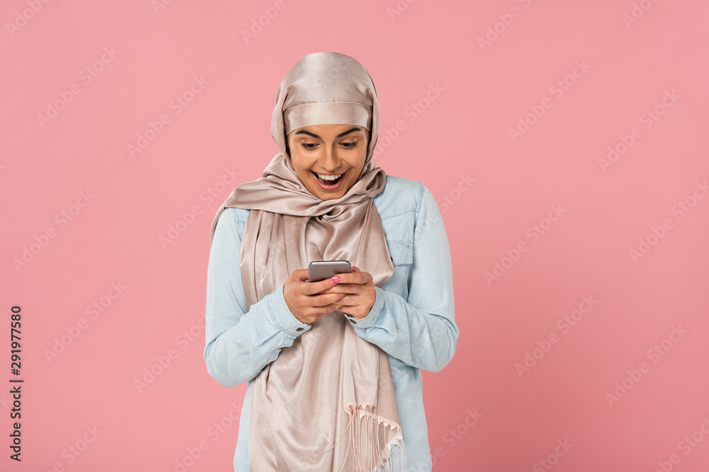 excited arabic girl using smartphone isolated on pink excited arabic girl using smartphone isolated on pink