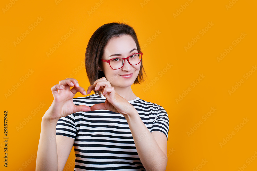 Close up photo portrait of lovely sweet cute asian girl giving you her heart isolated bright yellow background Close up photo portrait of lovely sweet cute asian girl giving you her heart isolated bright yellow background