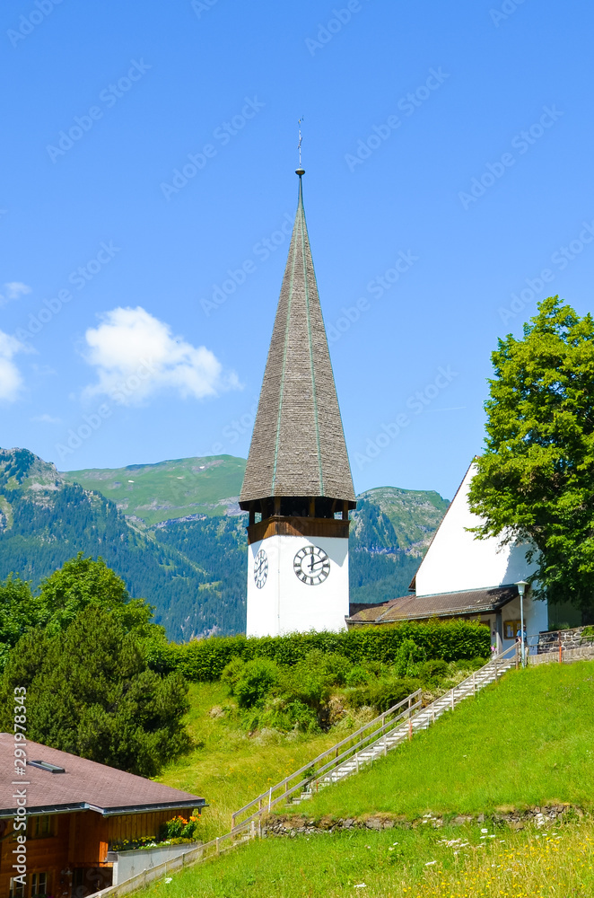 Beautiful Protestant church in Alpine resort Wengen, Switzerland photographed in the summer with green landscape. Mountains in the background. Alpine landscape, Swiss Alps. Vertical photography