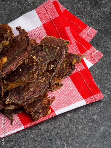 Φωτογραφία dried meat pieces, dehydrateed slices in spices, on the kitchen towel