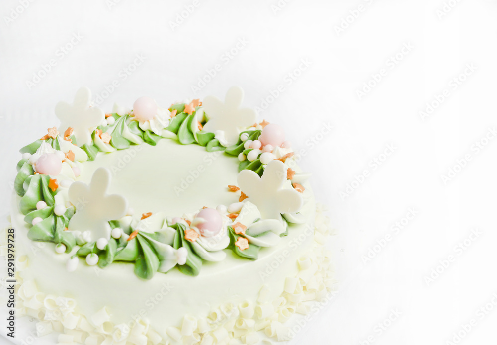 white chocolate birthday cake. is creamy, white and green, with beautiful spiral petals. On a white fabric background