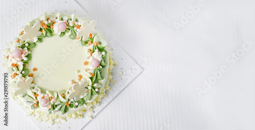 white chocolate birthday cake. is creamy, white and green, with beautiful spiral petals. On a white fabric background