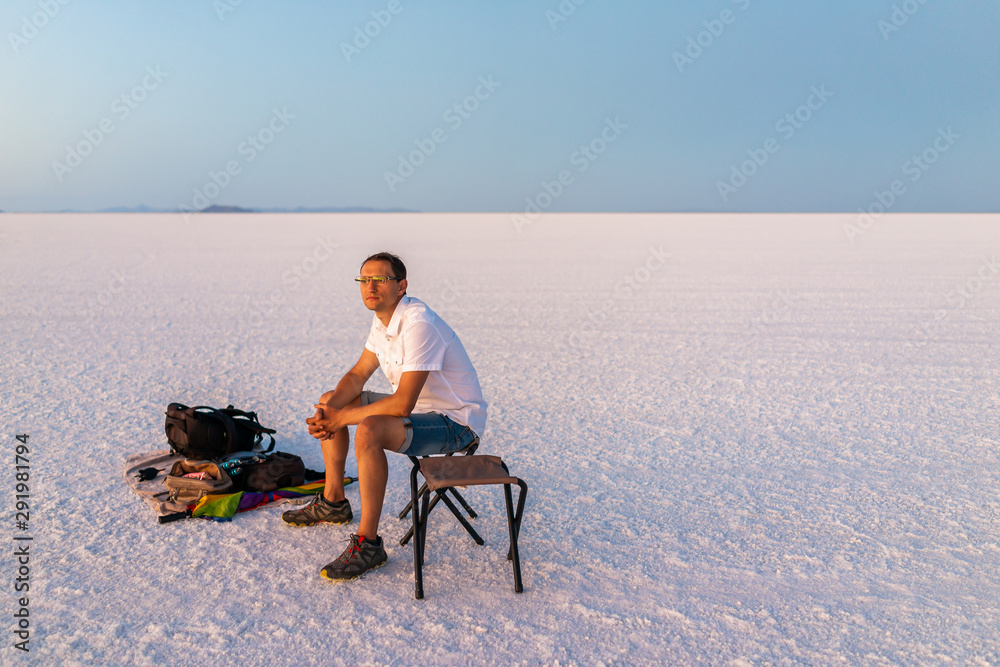 Bonneville Salt Flats near Salt Lake City, Utah at twilight after sunset with purple salt and man sitting watching view with horizon