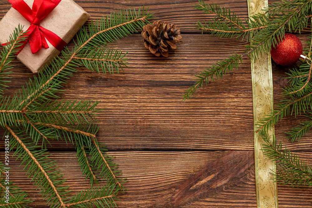 Fur spruce pine coniferous branches, gift box craft paper with red bow on the brown brushed wooden background Fur spruce pine coniferous branches, gift box craft paper with red bow on the brown brushed wooden background