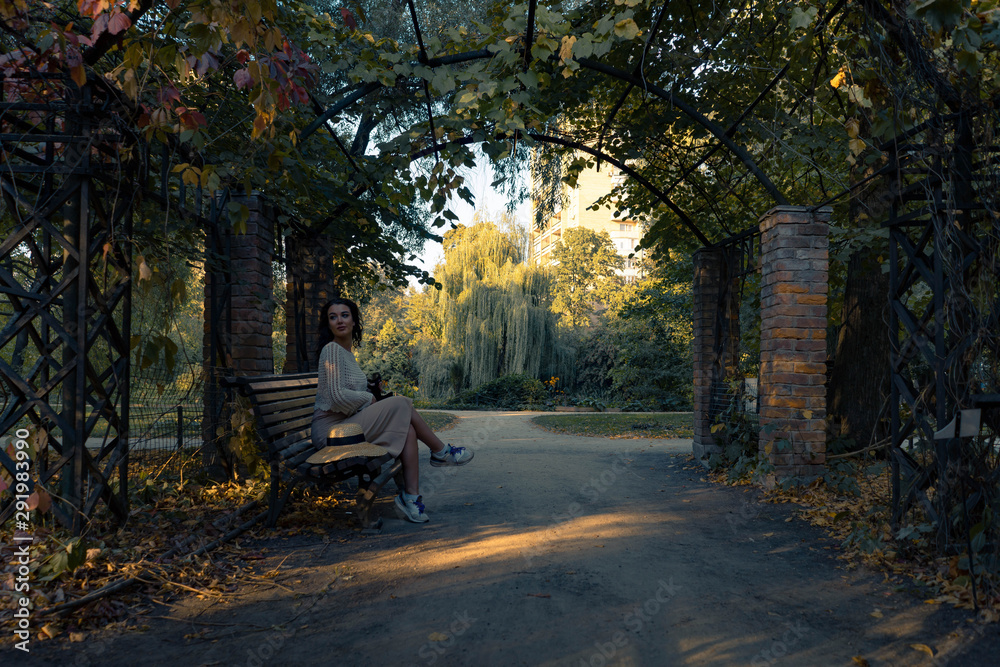 Woman in romantic attire relaxing outdoor in autumn park and enjoying good weather view on pond and sunset.