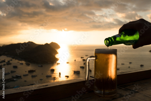 A bottle into a beer glass  with Sunset at Labuan Bajo, Flores, Indonesia photo