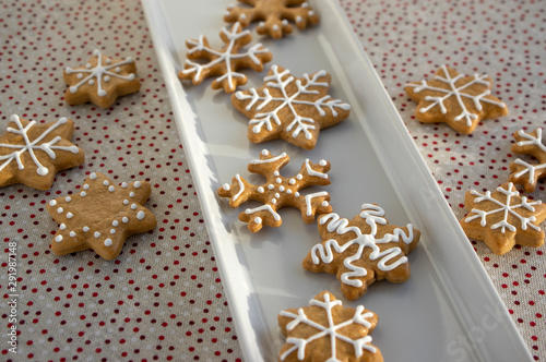 Painted traditional Christmas gingerbreads arranged on white dish in daylight, dotted tablecloth, common czech tasty sweets