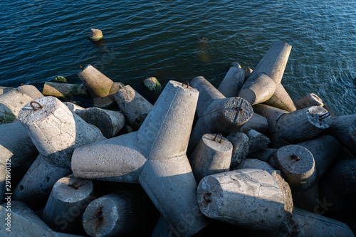 Tetrapod breakwaters in sea water. Beautiful sunset seascape with concrete tetrapodes for protect coastal structures from storm sea waves, effects of weather and longshore drift photo