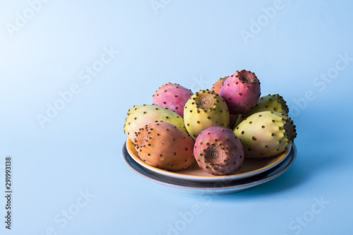 Whole fresh prickly pear fruit in a plate on a pastel blue background backdrop. Prickly pear or Fichi Dindia Salento, Puglia. Minimalism photo