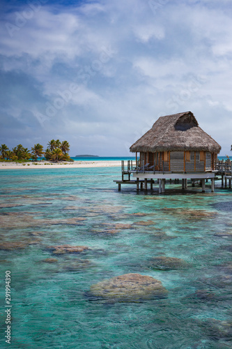 Fototapeta Vertical of overwater bungalow luxury resort in calm tropical lagoon paradise