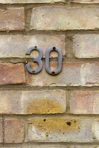House number 30 on a brick wall