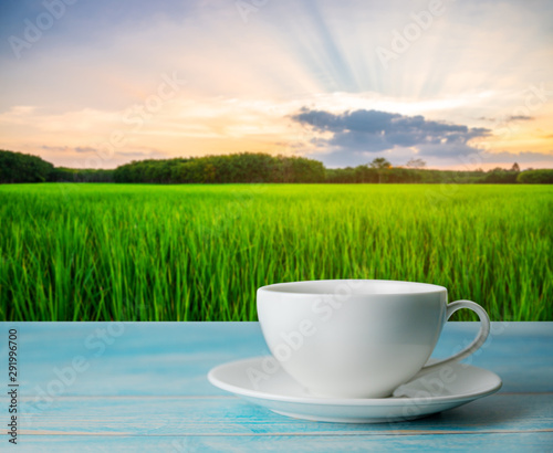 A cup of coffee with blurred rice field rural with colorful of sky in morning light