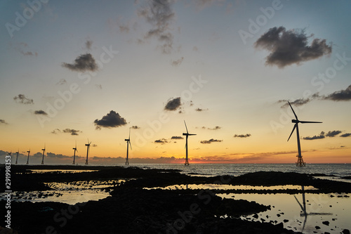 Landscape of western Jeju island at sunset with offshore wind turbines
