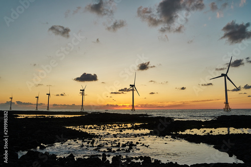 Landscape of western Jeju island at sunset with offshore wind turbines