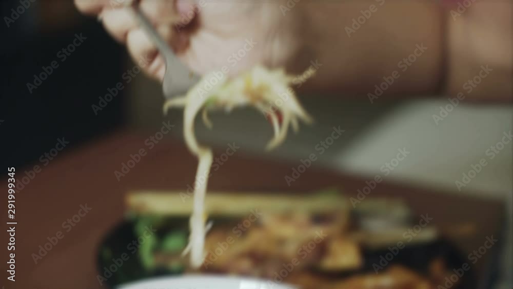 Young Asian Woman is eating green pappaya salad som tam closeup