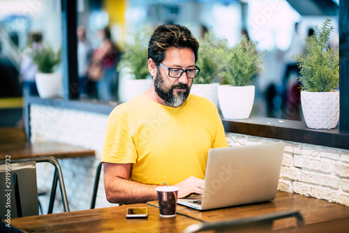 Bearded hipster man working at the laptop computer in the coffee bar with internet wifi connection free - alernative workstation for digital traveler - airport gate waiting for the flight photo