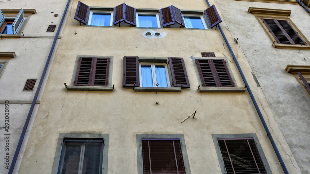 Sweet home. Wall of an old apartment house with many windows and brown window shutters. Memory.