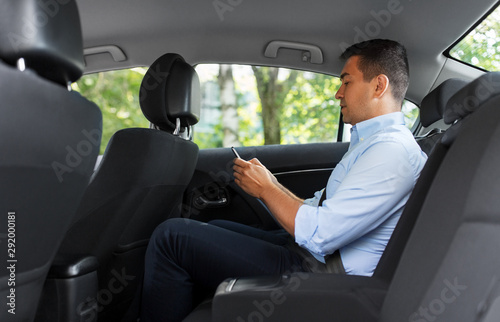 transport, business and communication concept - male passenger or businessman using smartphone on back seat of taxi car