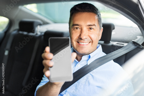 transport, business and technology concept - smiling male passenger or businessman showing smartphone on back seat of taxi car © Syda Productions