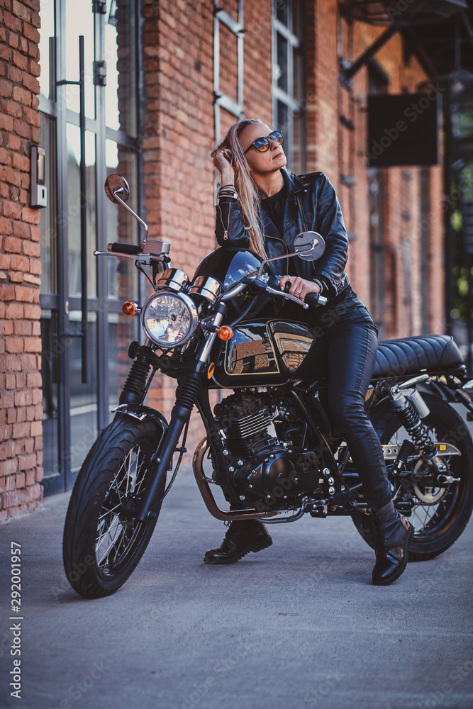 Stylish mature female is posing on photographer on her new shiny retro bike.