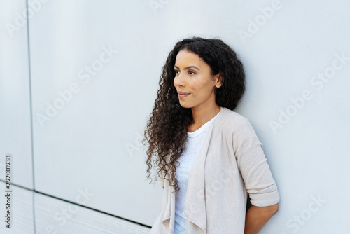Young woman relaxing against a wall thinking