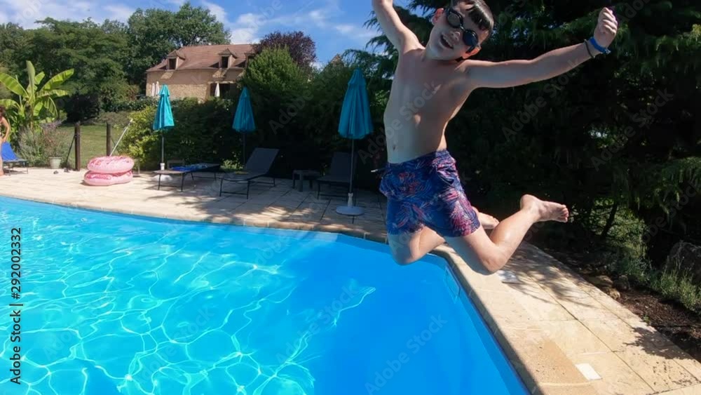 Child jumping in a summer vacation pool at the start of the holidays. Happy action shot in slow motion
