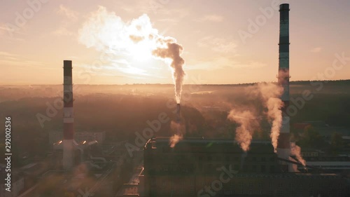 Factory chimneys producing smoke at sunrise, aerial view. Concept of air pollution, environment and ecology crisis, climate change, global warming.
